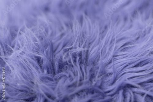 Purple soft fur for background or texture. Fluffy blue fur blanket. The color of 2022 very peri. Flat lay, top view, copy space