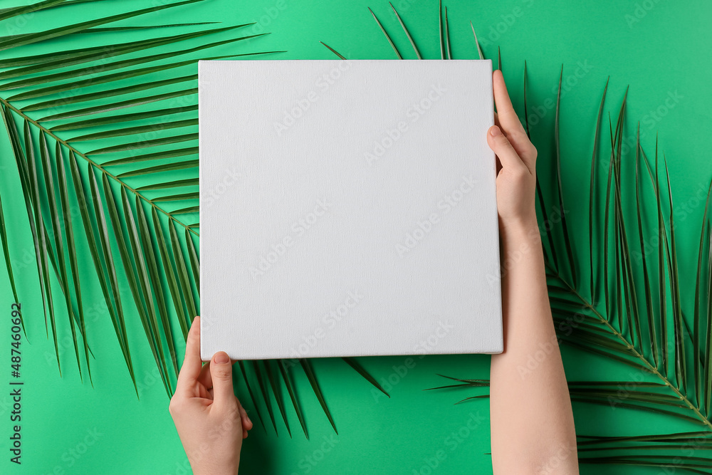 Female hands with blank poster and palm leaves on green background Female hands with blank poster and palm leaves on green background