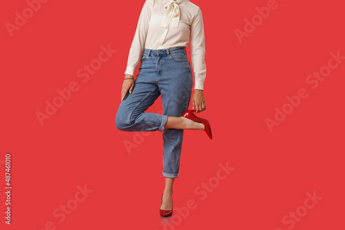 Photographie Fashionable young woman in stylish jeans on color background