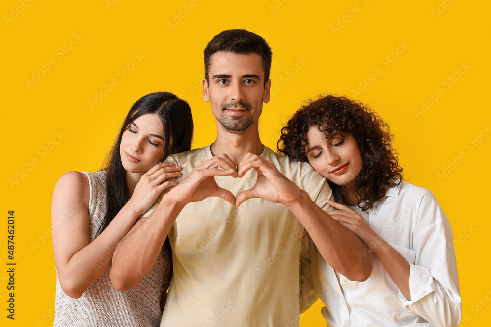 Man and two beautiful women on color background. Polyamory concept Man and two beautiful women on color background. Polyamory concept