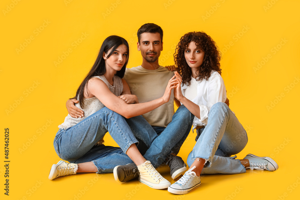 Man and two beautiful women on color background. Polyamory concept Man and two beautiful women on color background. Polyamory concept