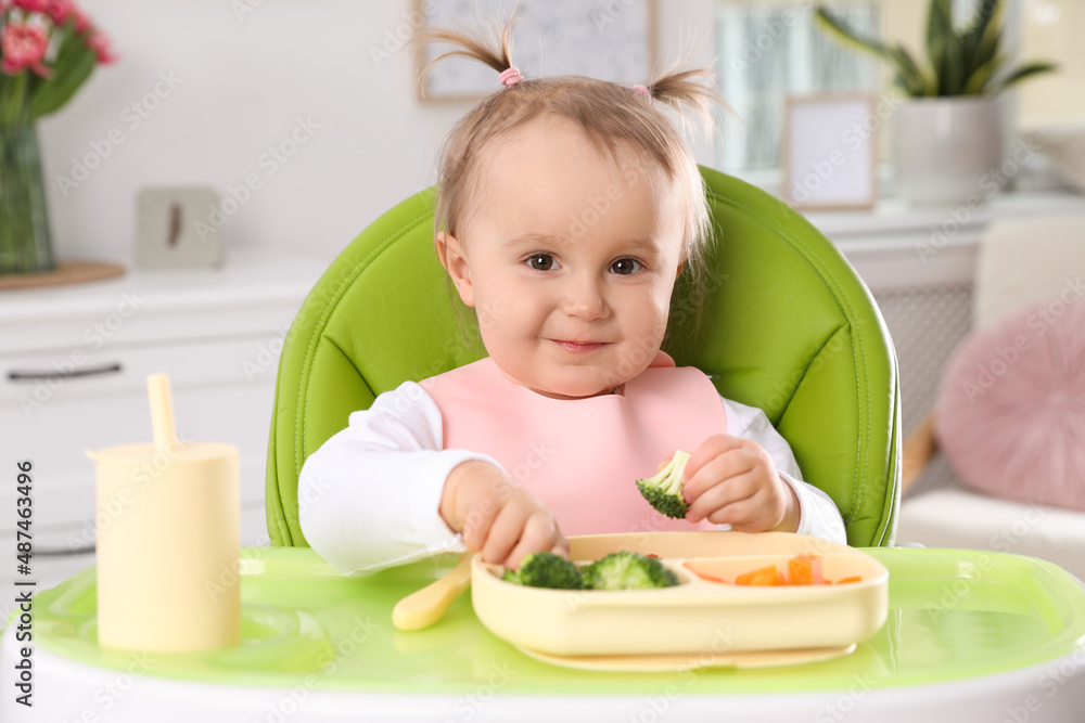 Cute little baby eating food in high chair at home Cute little baby eating food in high chair at home