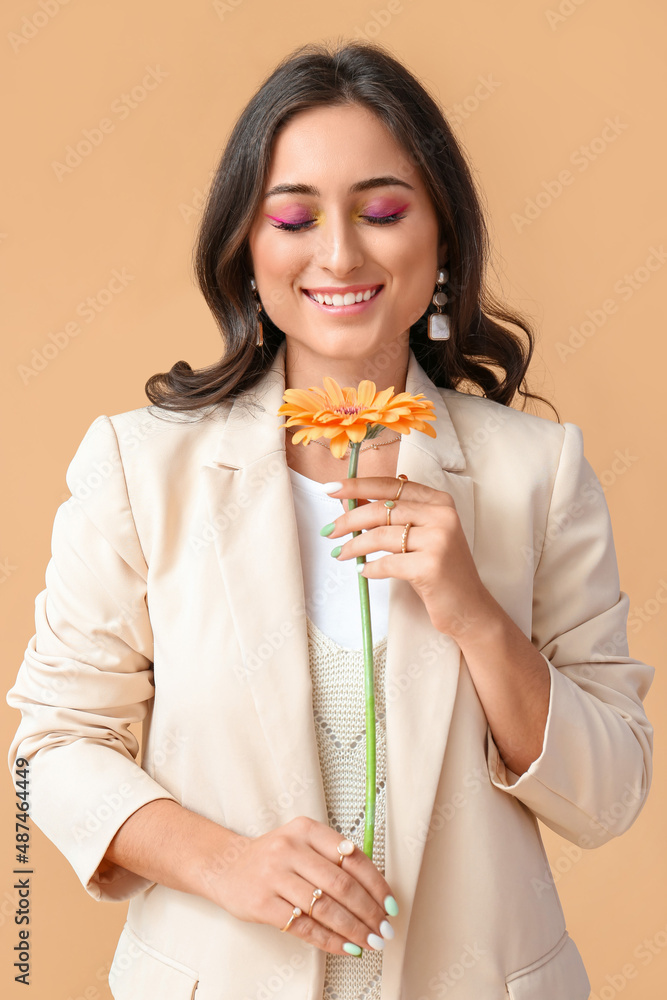 Woman with creative makeup and stylish jewelry holding gerbera flower on color background. International Women's Day Woman with creative makeup and stylish jewelry holding gerbera flower on color background. International Women's Day