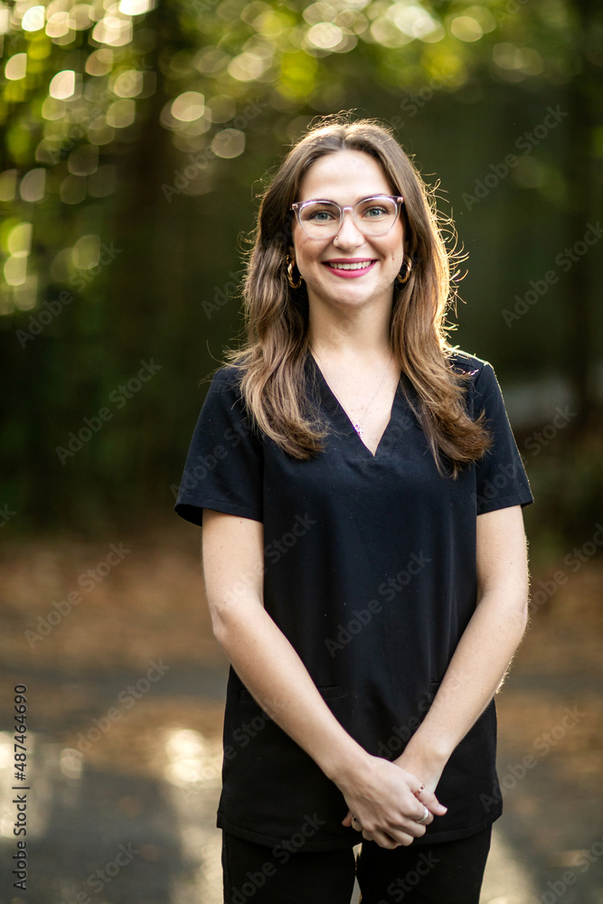 A medical professional with black scrubs outside in a natural background with copy space.