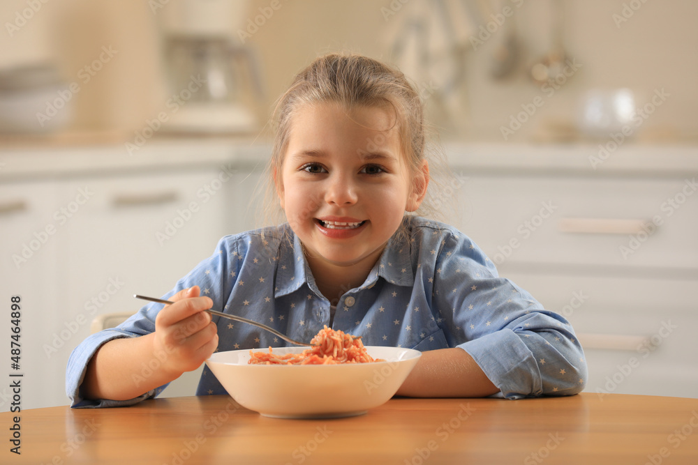 Cute little girl eating tasty pasta at table in kitchen Cute little girl eating tasty pasta at table in kitchen