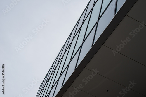 The exterior wall of a contemporary commercial style building with aluminum metal composite panels and glass windows. The futuristic building has engineered diagonal cladding steel frame panels.