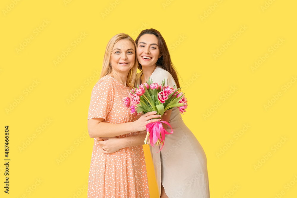 Beautiful women with bouquet of flowers on yellow background. International Women's Day celebration Beautiful women with bouquet of flowers on yellow background. International Women's Day celebration