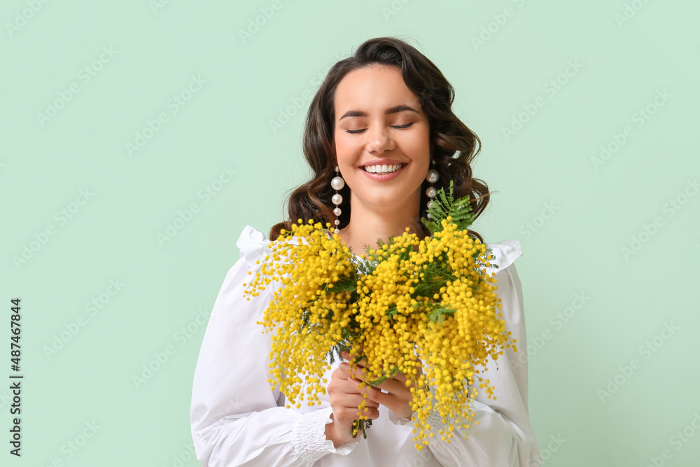 Beautiful young woman with bouquet of mimosa flowers on green background Beautiful young woman with bouquet of mimosa flowers on green background