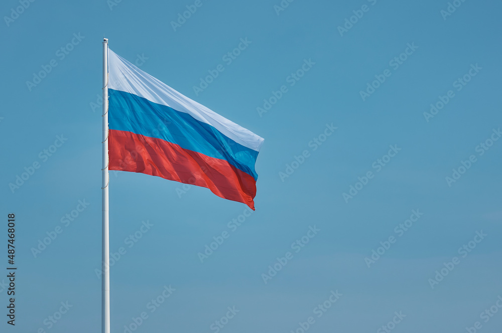 Flag of Russia against the blue sky. High flagpole on the embankment of the city of Blagoveshchensk, Russia. The tricolor cloth moves smoothly in the wind. Room for text. Flag of Russia against the blue sky. High flagpole on the embankment of the city of Blagoveshchensk, Russia. The tricolor cloth moves smoothly in the wind. Room for text.