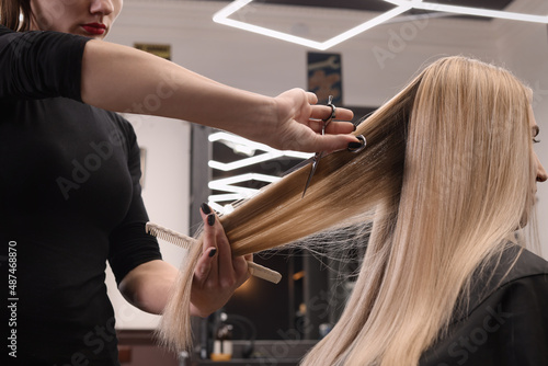 Fototapeta samoprzylepna Professional hairdresser cutting woman's hair in salon, closeup