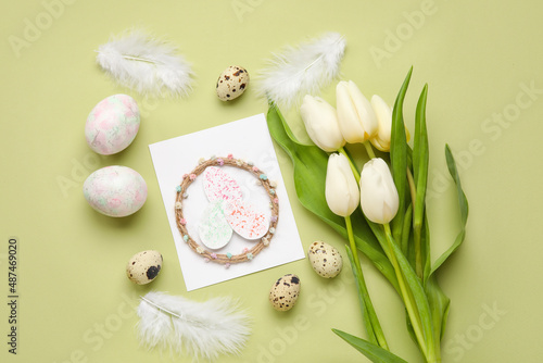 Beautiful Easter composition with greeting card, eggs and flowers on color background