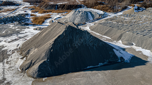 Massive piles of gravel, rock, and stone at a rock quarry in winter with no sign of activity.