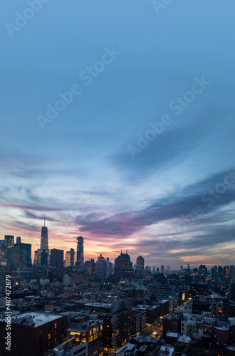 New York City skyline lights at dusk with empty blue sky above the buildings of Lower Manhattan