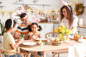 Happy family at dining table in kitchen on Easter day