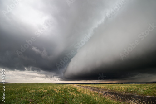 A thick shelf cloud approaches as a powerful storm moves across a field in the plains.
