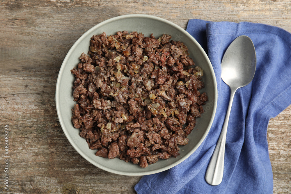 Fried minced meat, spoon and napkin on wooden table, top view Fried minced meat, spoon and napkin on wooden table, top view