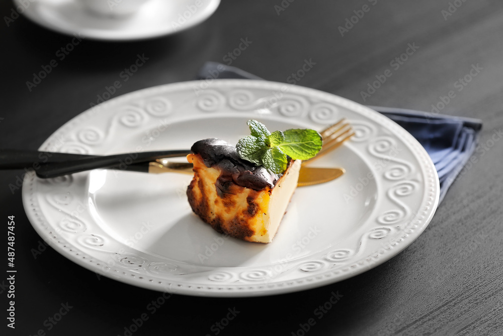 Plate with slice of tasty Basque burnt cheesecake on table Plate with slice of tasty Basque burnt cheesecake on table