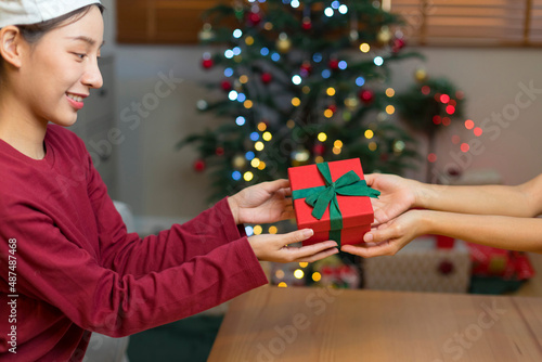 woman giving Christmas and New Year Gift box to woman at Home. Family Xmas celebration. Person Holding, Receiving a Gift box.