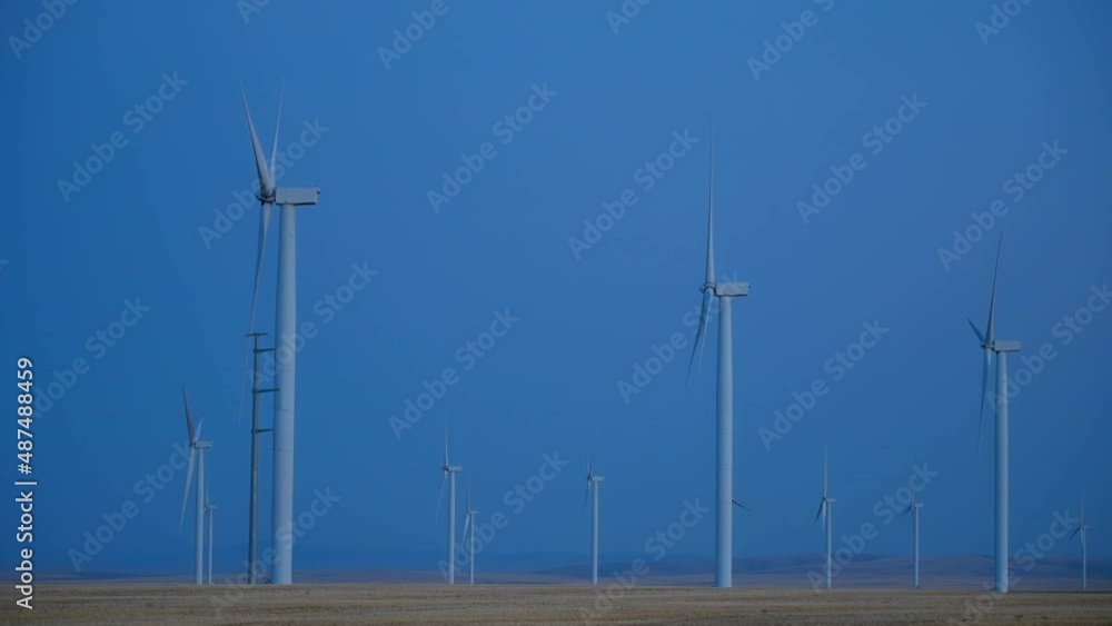 Side View Of Wind Turbines Generating Wind Energy At The Farm Against Clear Sky At Dusk. wide Side View Of Wind Turbines Generating Wind Energy At The Farm Against Clear Sky At Dusk. wide