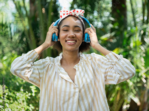 Portrait happy young woman with headphone in the garden 