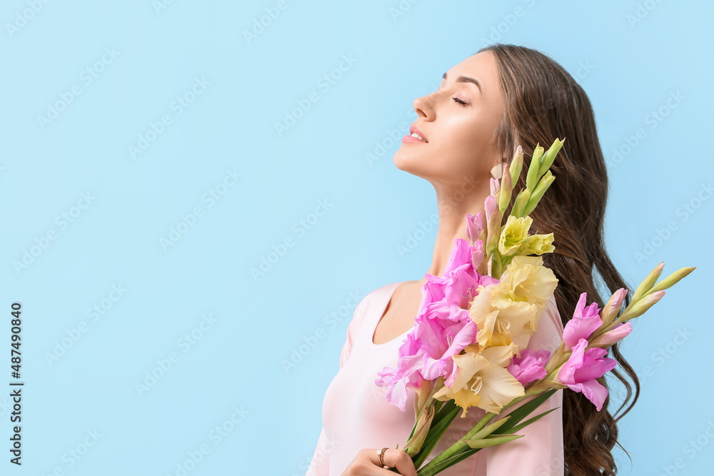 Elegant woman with closed eyes and bouquet of Gladiolus flowers on color background