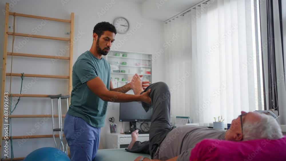 Physiotherapist exercising with senior patient's leg in a physic room. Physiotherapist exercising with senior patient's leg in a physic room.