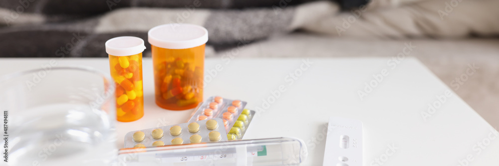 Thermometer with pills on table against background of sick lying woman Thermometer with pills on table against background of sick lying woman