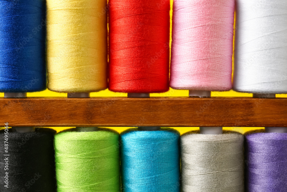 Closeup view of spools with sewing threads on yellow background Closeup view of spools with sewing threads on yellow background