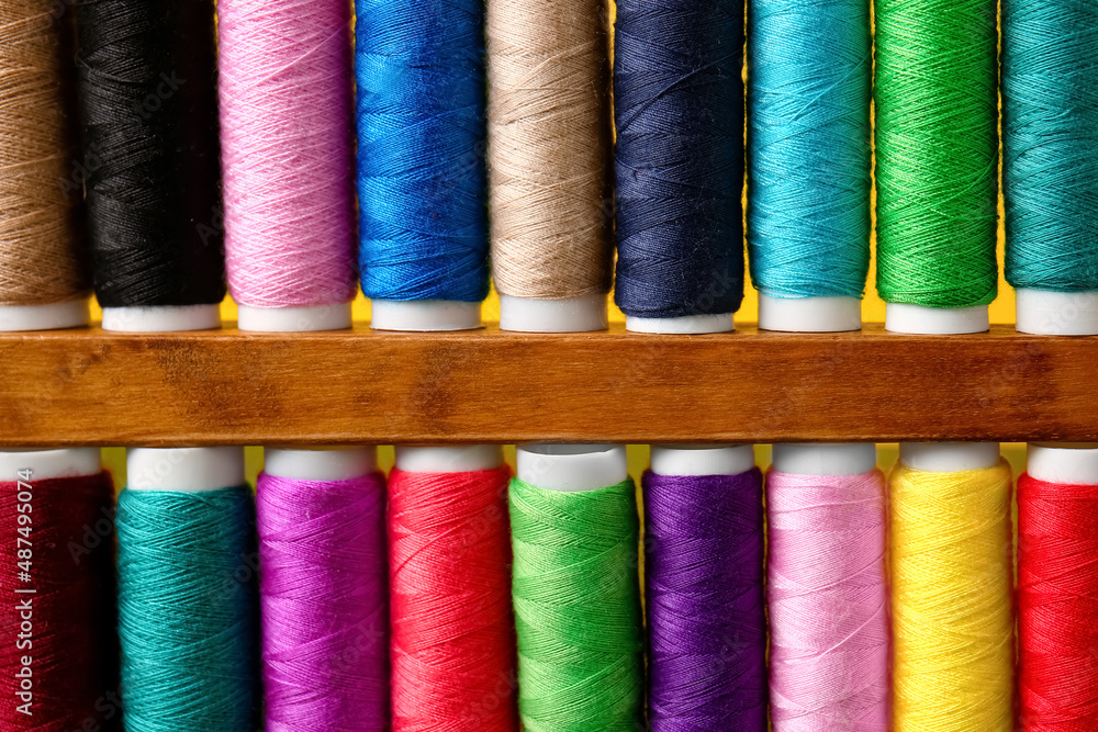 Spools with sewing threads on yellow background, closeup Spools with sewing threads on yellow background, closeup