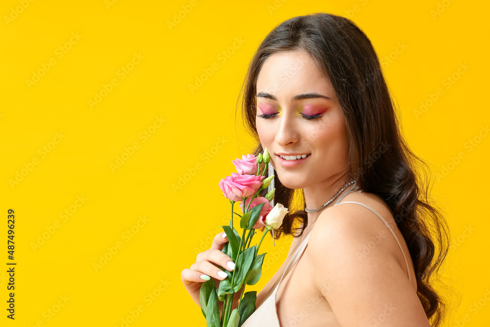 Woman with creative makeup and closed eyes holding eustoma flowers on yellow background. International Women's Day Woman with creative makeup and closed eyes holding eustoma flowers on yellow background. International Women's Day