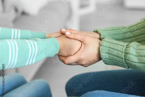 Little girl and her mother in warm sweaters holding hands at home  closeup