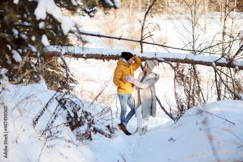 Romantic couple having fun in the snowy forest, spending time together at valentine's day.