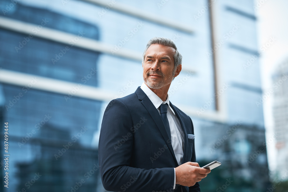 Hard work, determination, persistence creates a boss. Shot of a handsome mature businessman in corporate attire using a cellphone outside outside during the day. Hard work, determination, persistence creates a boss. Shot of a handsome mature businessman in corporate attire using a cellphone outside outside during the day.