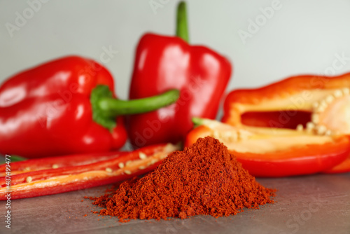 Fresh chili and bell peppers with paprika powder on grey table, closeup photo