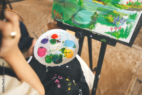 Woman painting brush on canvas at workshop art lesson class focus on palette. photo