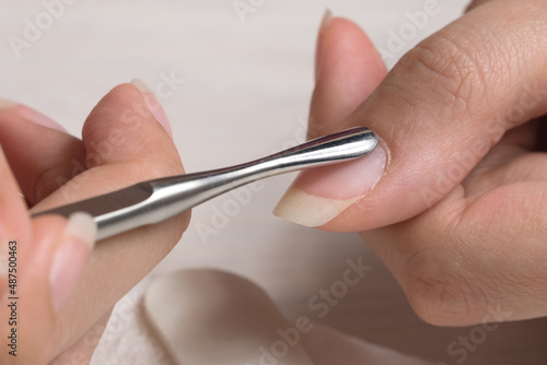 Manicure. Push back the cuticle with a metal pusher. Getting injured during a manicure. Skin care, hygiene. Spa, nail salon. Home care. Beauty.
