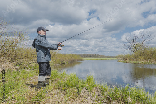 Fisherman in a jacket throws a spinning rod.