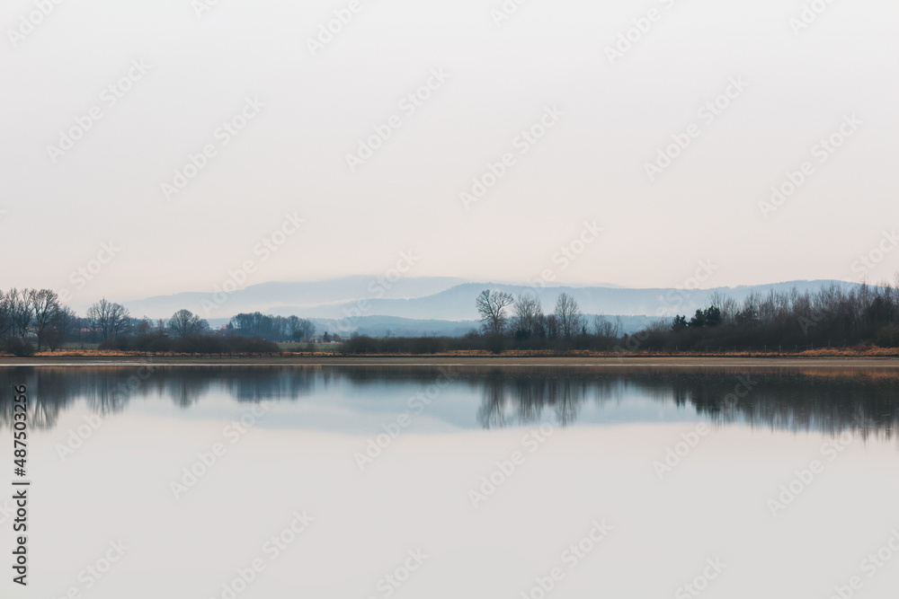 Pond with trees, fog and hill Klet at rainy moody weather. Line of Czech landscape with lots of negative space