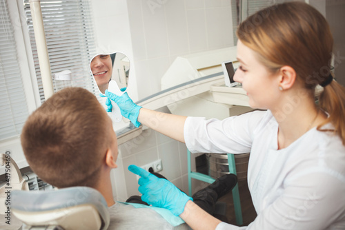 dentist shows patient his white beautiful teeth in mirror.