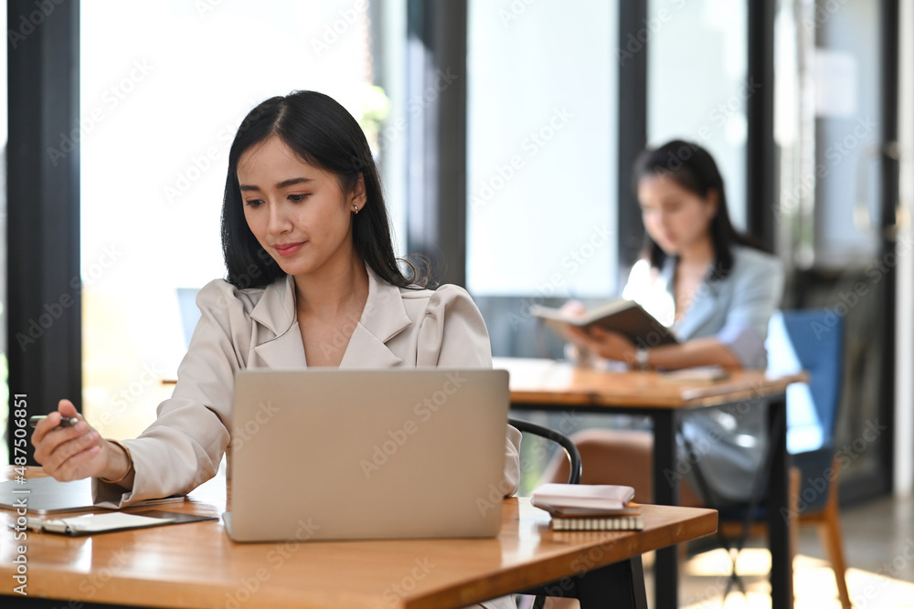 Thoughtful young asian woman working with computer laptop at office. Thoughtful young asian woman working with computer laptop at office.