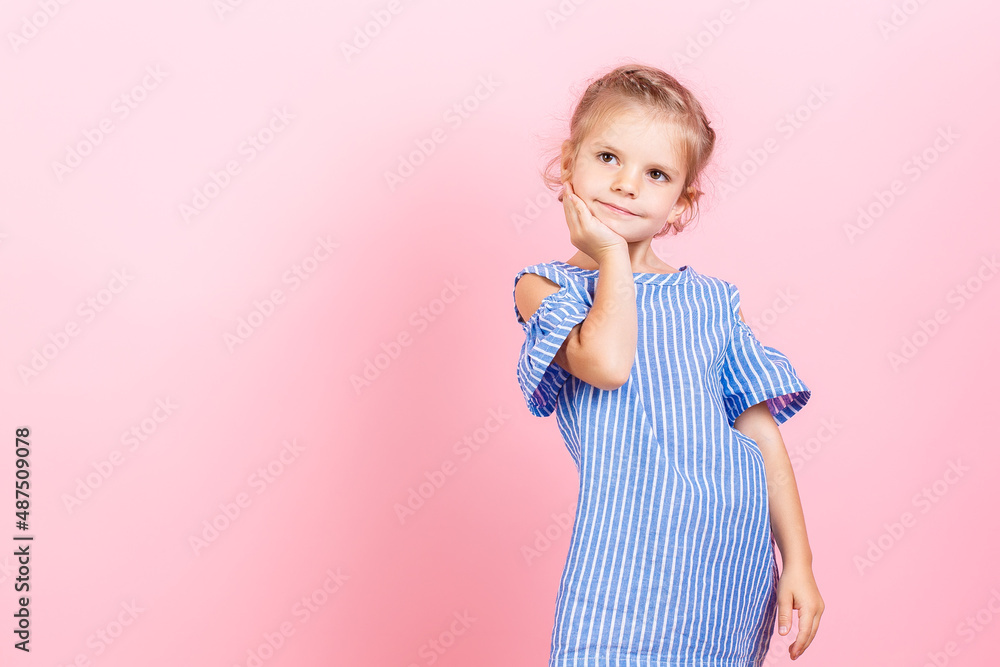 Portrait of cute little child girl wears blue dress while posing over pink studio background Portrait of cute little child girl wears blue dress while posing over pink studio background