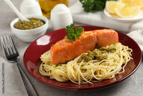 Delicious spaghetti with salmon and pesto sauce on light grey table, closeup