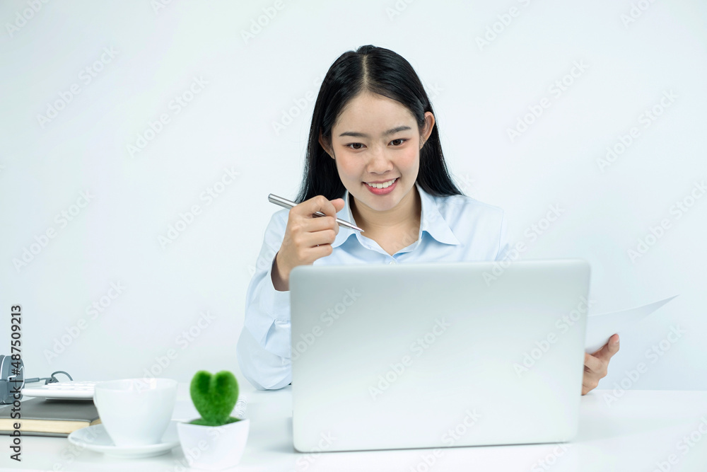 Asian woman working on a laptop with a cheerful and happy smile while working and take notes at the office Asian woman working on a laptop with a cheerful and happy smile while working and take notes at the office