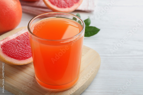 Tasty freshly made grapefruit juice on white wooden table. Space for text