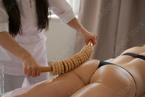 Stimulation lymphatic system with wood therapy treatment. Massage with wooden roller to eliminate liquids and cellulite. Improve circulation in the legs. Aesthetic tools photo
