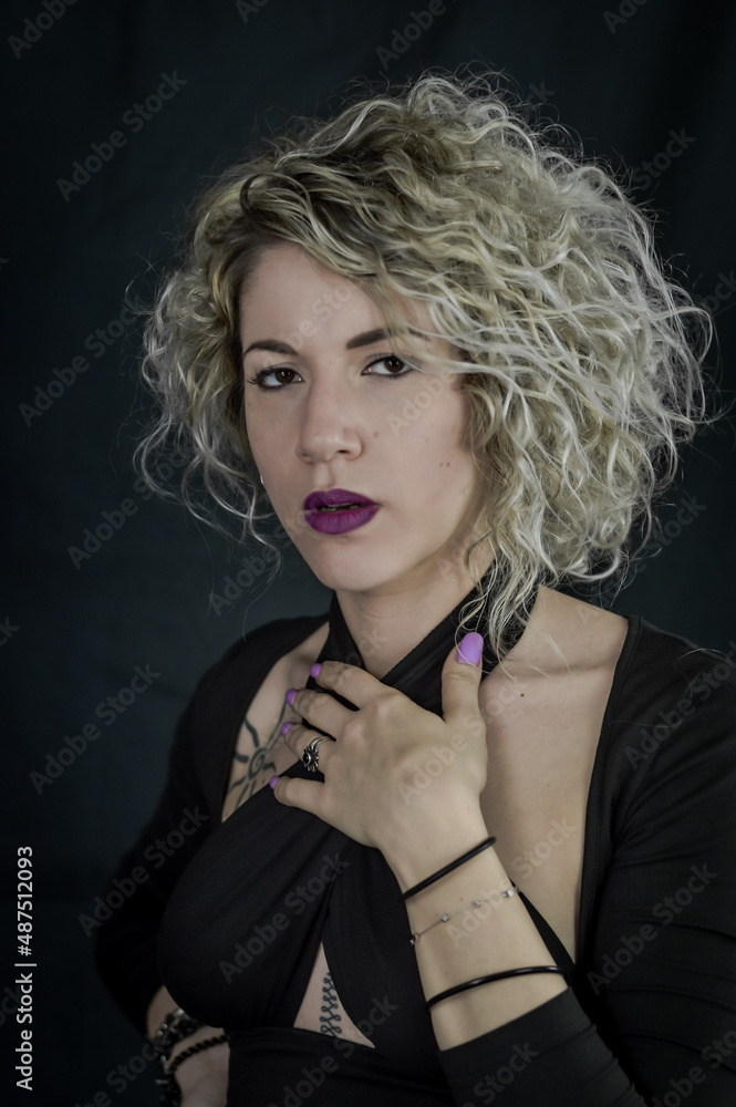 Obraz premium Portrait of a beautiful curly blonde woman who looks indignant with her hand on her chest