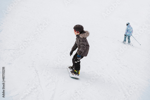 little boy learning to ride on snowboard