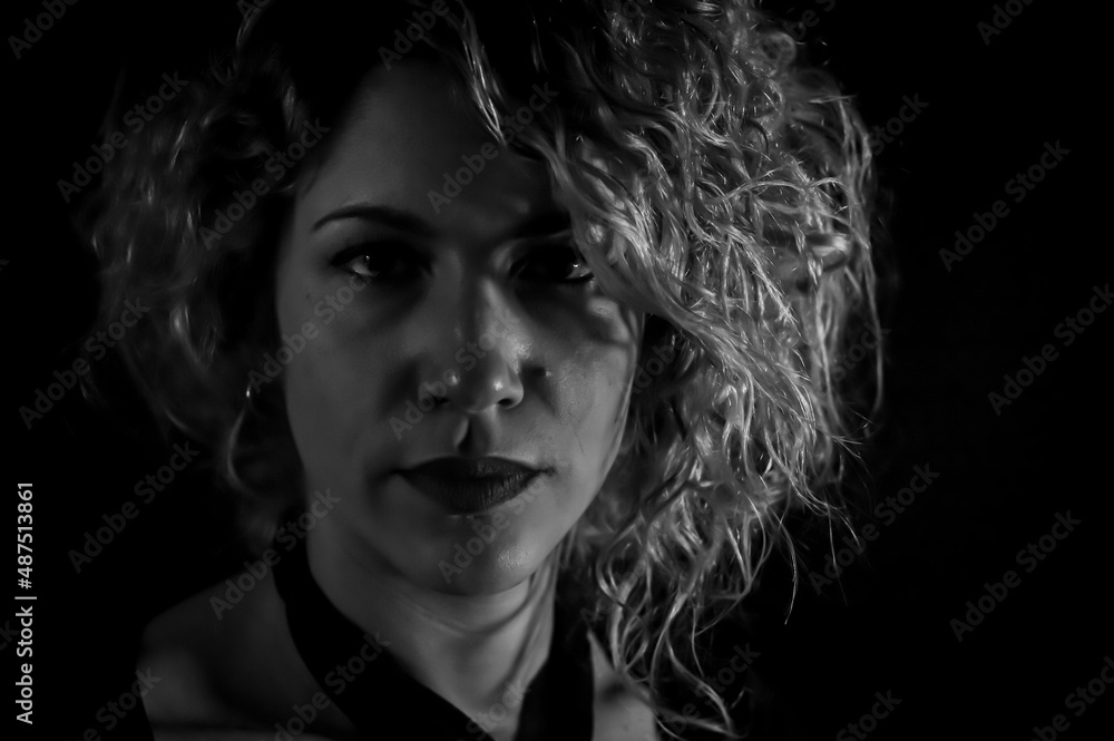 Black and white portrait of a beautiful curly blonde woman who is looking seriously in front of her