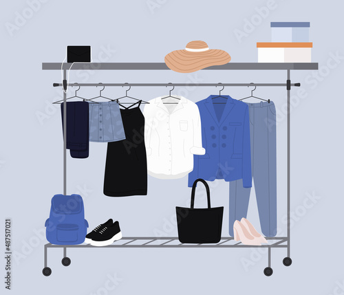Stylish fashion clothes hanging on hangers on garment rack or rail. Fashion clothes and accessories on hanger rail. Fall, winter garments, footwear and bags. Women capsule wardrobe on racks.