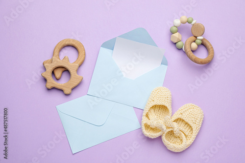 Envelopes for baby shower and accessories on lilac background, flat lay